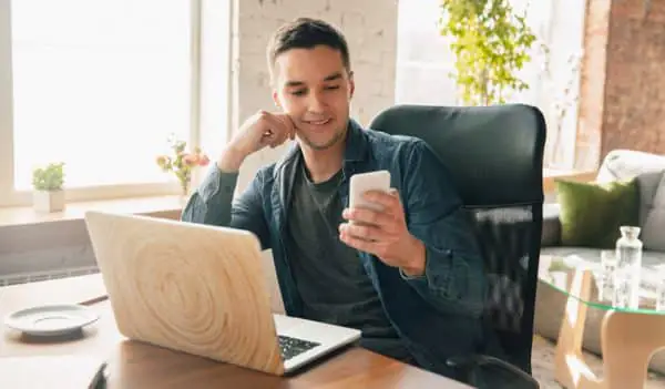 ergonomia no trabalho home office - pessoa olhando celular enquanto trabalha