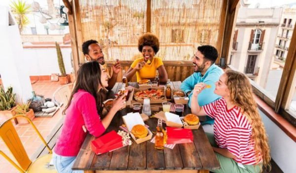 Grupo de amigos consumindo refeições e bebidas em um restaurante ao ar livre