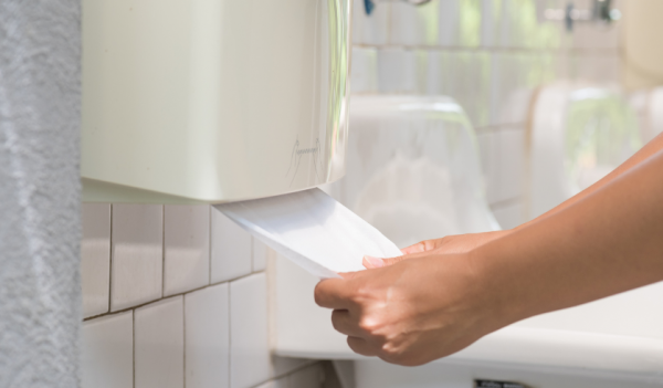 Pessoa puxando papel de um dispenser com as duas mãos